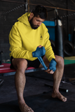 MMA  fighter  in super driven bee  focused  sun yellow hoodie wrapping his fist